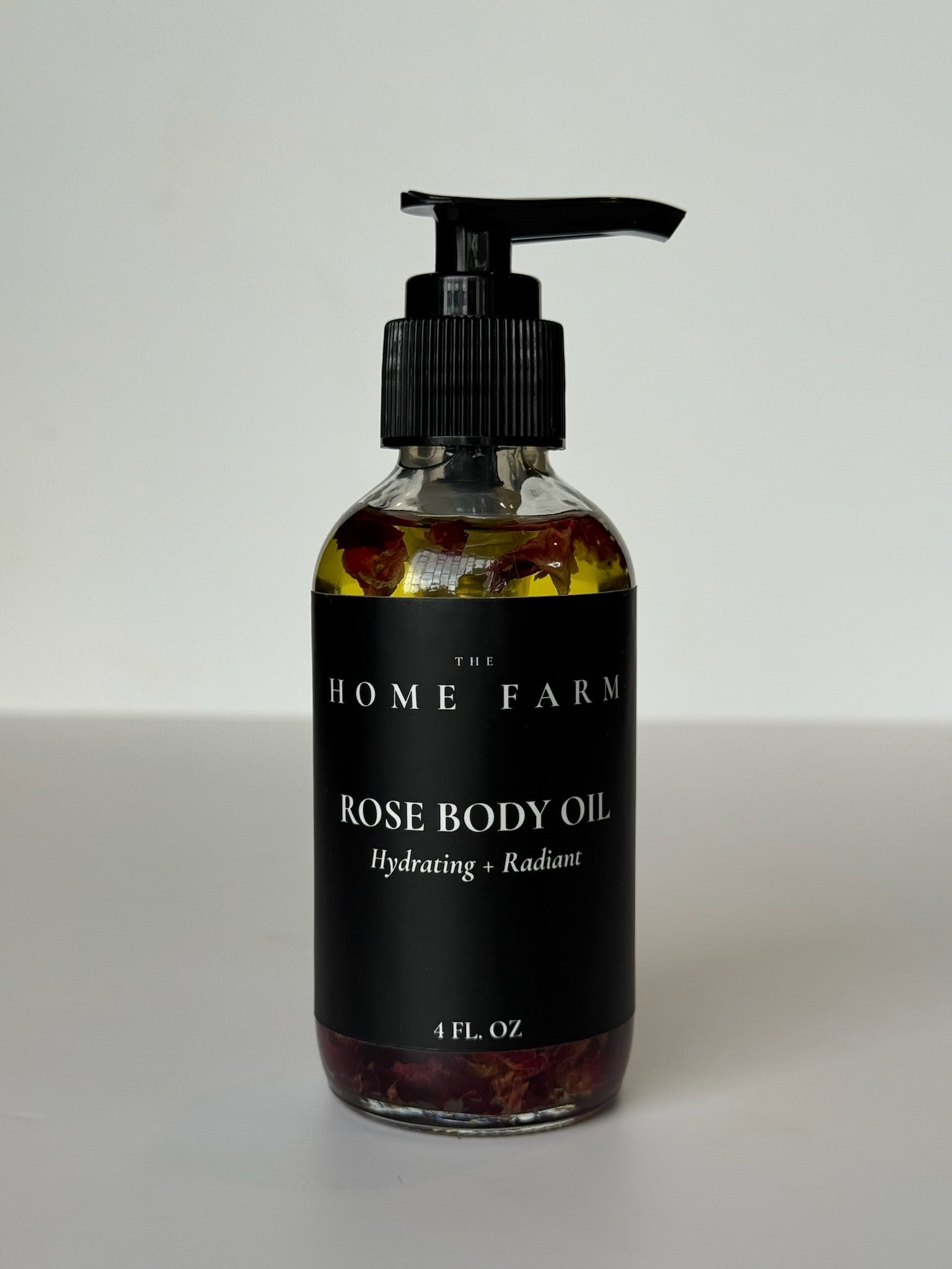Rose Body Oil bottle displaying golden elixir with fresh rose petals